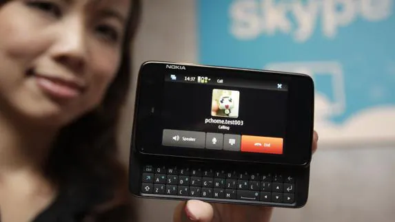 Una mujer muestra un Smartphone que puede hacer llamadas con Skype. 