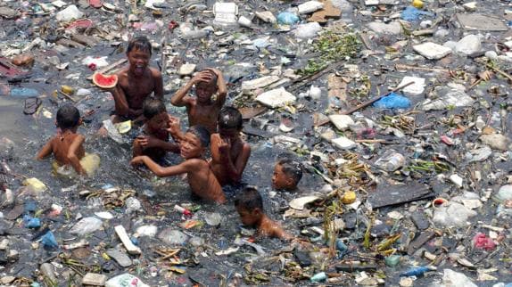 Unos niños juegan en un río lleno de basura en Manila. 