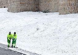 Dos operarios limpian de nieve una de las aceras que circundan la muralla de Ávila. RAÚL SANTIDRIÁN