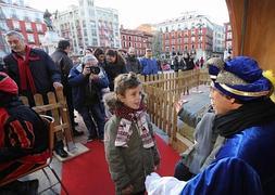 El Cartero Real recibe a dos niños en su trono de la Plaza Mayor de Valladolid para conocer sus peticiones a los Reyes Magos./ H. Sastre
