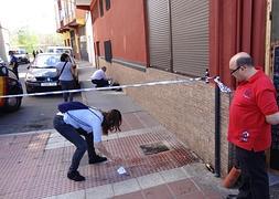 Un vecino observa a la puerta del bar dond se encontraba el herido como un investigador busca pruebas. / R . Otazo