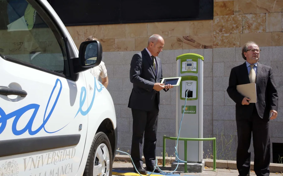 Carlos Bergera, conecta el cargador de una de las furgonetas eléctricas de la Universidad, junto al vicerrector, Ricardo López. 