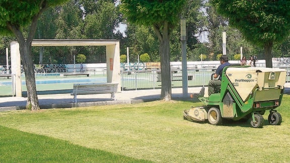 Un trabajador siega el césped de las piscinas del Sotillo.