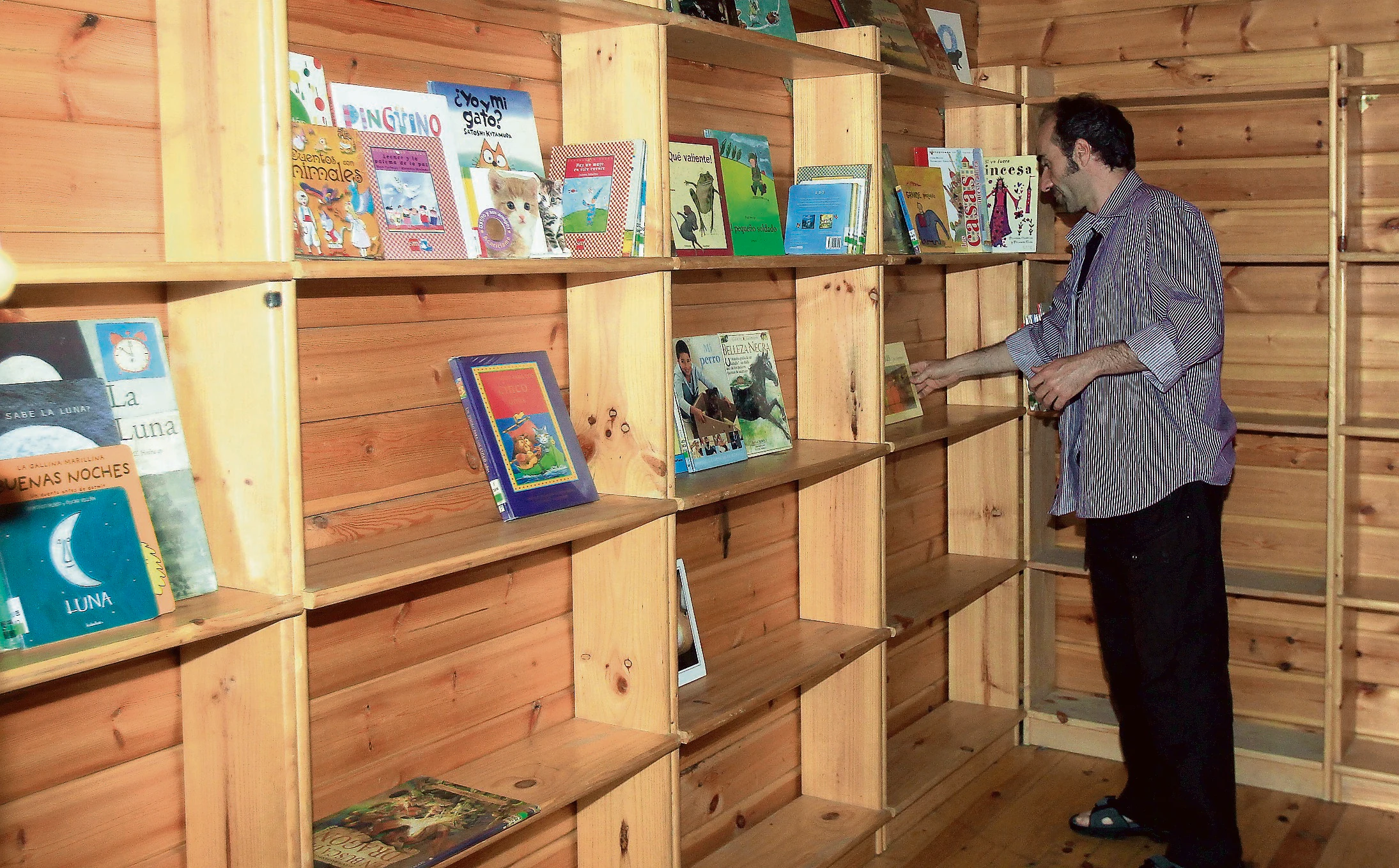 Un bibliotecario coloca ayer los libros infantiles y juveniles en la caseta instalada en el parque de la Huerta de Guadián.