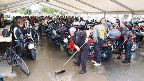 Una persona de la organización retira el agua acumulada en la carpa a causa del aguacero caído ayer. José Carlos Diez
