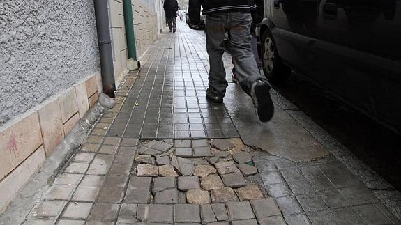 Un hombre camina por una acera en mal estado