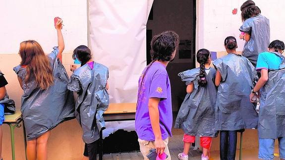 Los niños del campamento pintan el muro de las dependencias parroquiales. 
