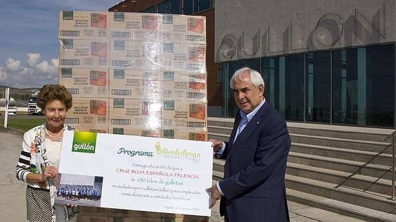 María Teresa Rodríguez Sainz-Rozas, presidenta de Gullón, a la izquierda, entrega a Javier Bravo, presidente de Cruz Roja Palencia, un cheque por valor de 650 kilos de galletas. 