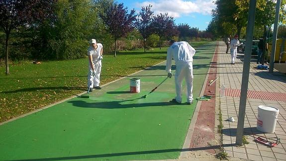 Dos operarios trabajan en el carril bici.