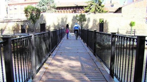 Dos personas cruzan la pasarela junto al parque de la Cascajera.
