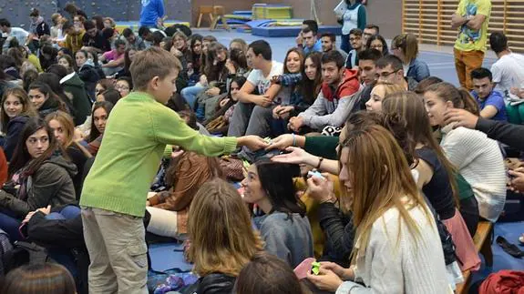 Uno de los alumnos del Narciso Alonso Cortés reparte material para un experimento entre los universitarios.