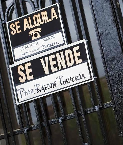 Carteles de 'Se alquila' y 'Se vende' cuelgan de la puerta de entrada de un edificio.