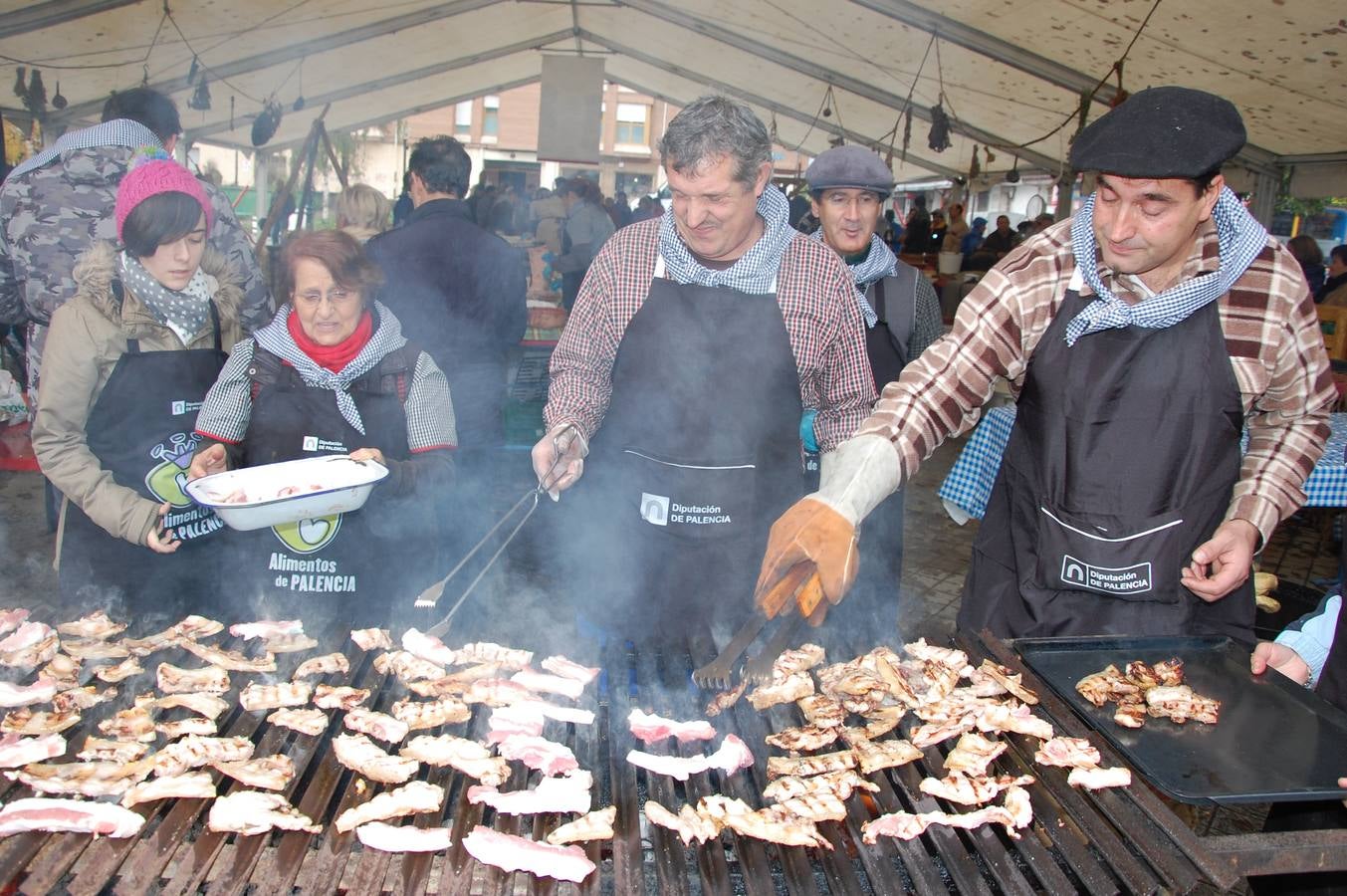 Vecinos y colaboradores preparan carne a la brasa. 