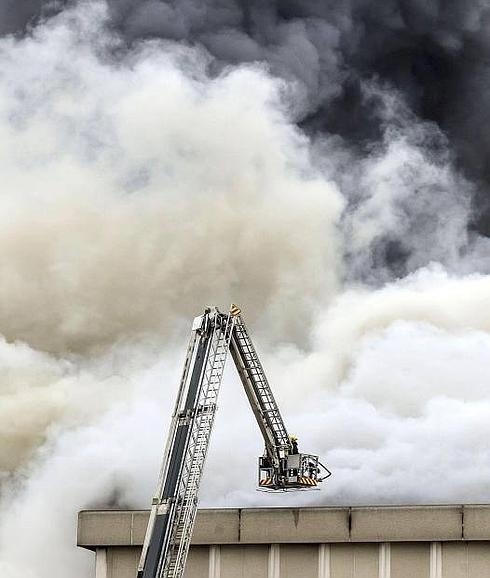 Dos bomberos contemplan el incendio desde el brazo articulado. 