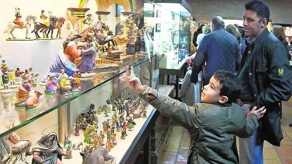 Un niño señala las figuras durante la visita a la exposición de belenes, en la jornada de inauguración.
