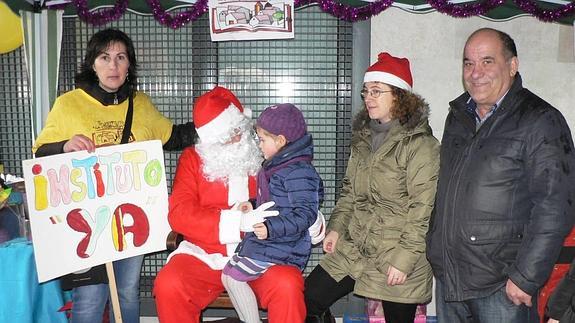 Nuria Blanco, de la comisión PRO-IES (camiseta amarilla) y el alcalde de La Cistérniga, Mariano Suárez (derecha) escoltan a Papá Noel que recogió los deseos de los más pequeños y sus padres de tener un instituto en la localidad.  