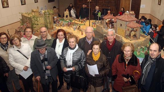 Los vecinos que han colaborado en el montaje posan frente al belén, instalado en la ermita del Cristo del Mercado.
