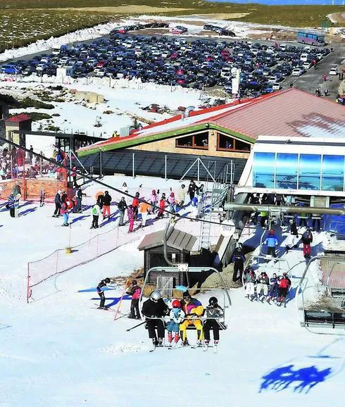 Algunos esquiadores disfrutando ayer de la nieve, con el parking de la estación lleno. 