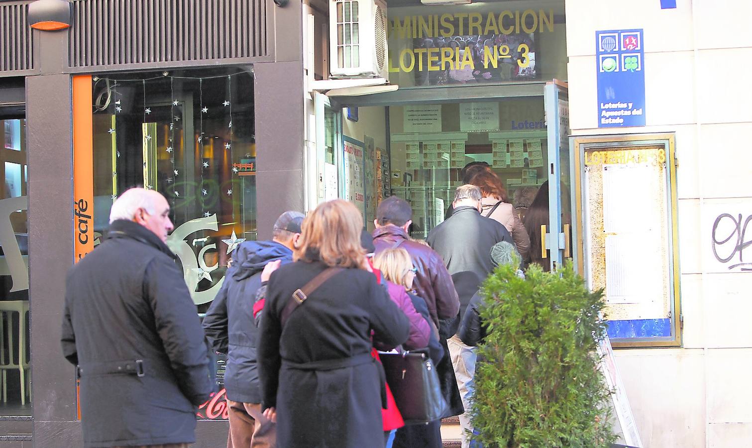 Varias personas guardan cola en la administración de la Calle Mayor que vendió un décimo del segundo premio en Navidad.
