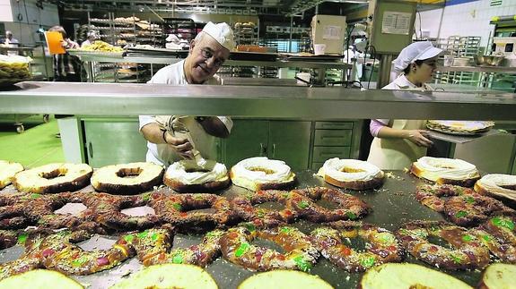 Un veterano repostero rellena de nata los roscones en el obrador de Gil.