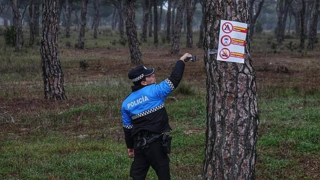 Una agente de la policía local de Valladolid coloca carteles avisando de que no se puede acampar en el Pinar. 