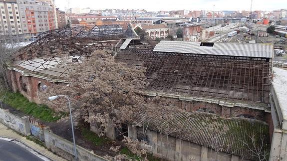 La cubierta del depósito de locomotoras, con la estación al fondo, muestra su entramado metálico al retirarse las uralitas, salvo en la parte superior del tejadillo de la derecha y en las naves anexas. 