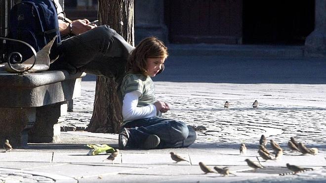 Una niña da de comer a los gorriones en la Plaza Mayor de Segovia. 