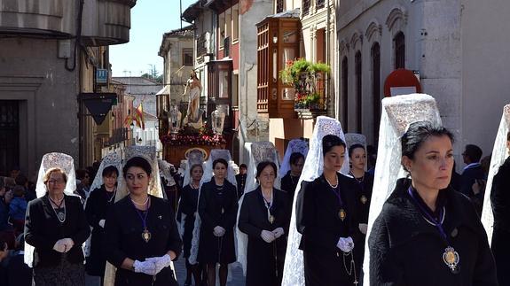 Mujeres con mantillas blancas caminan delante de las imágenes. 