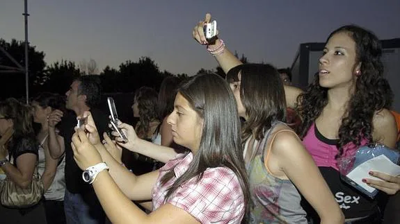 Varias jóvenes hacen foto con su móvil en un concierto.