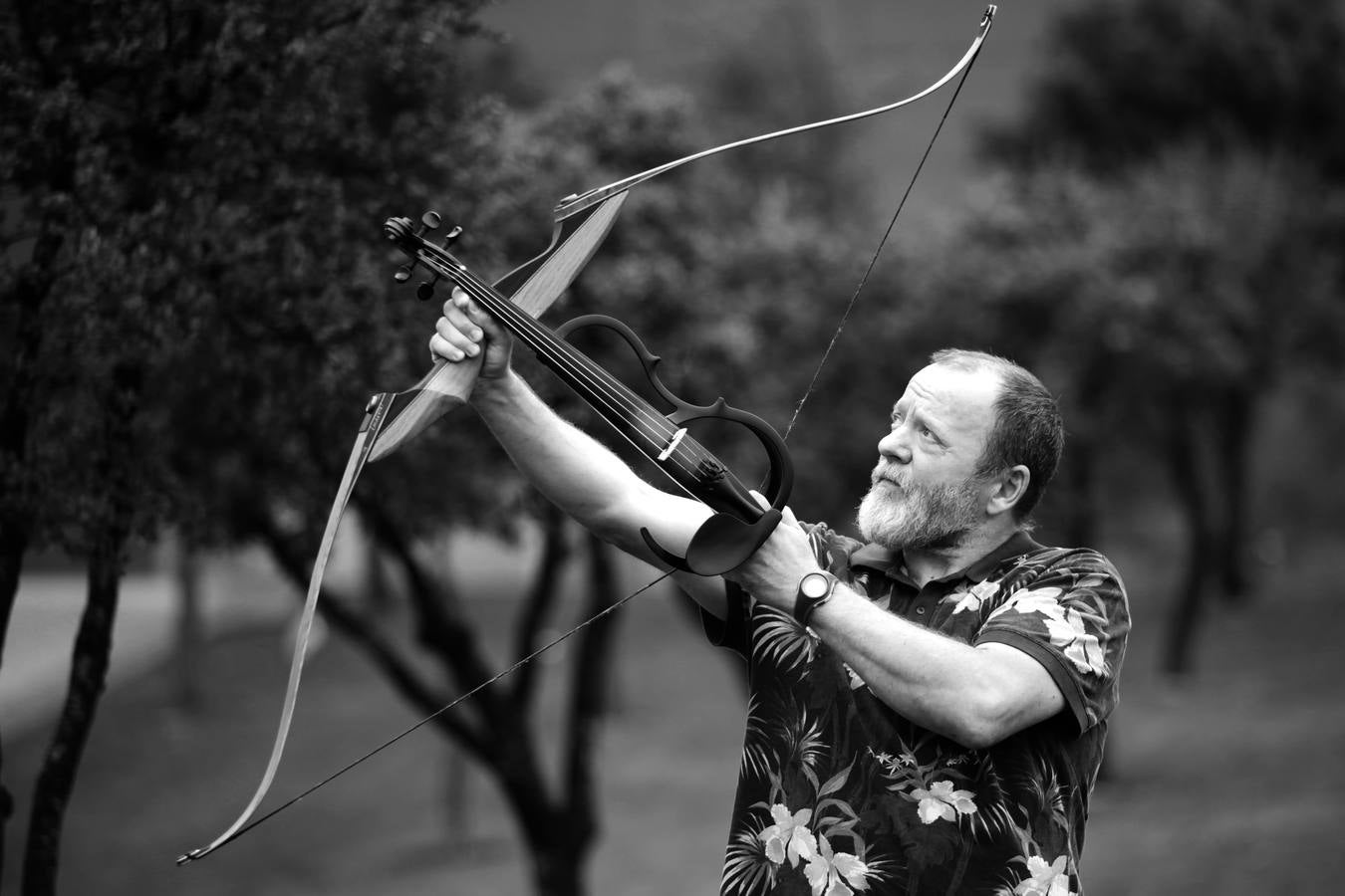 Vladimo apunta con el arco de tiro, haciendo su violín electrónico las veces de flecha. 