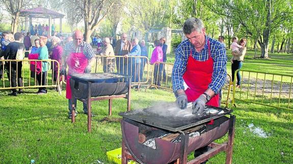 Los vecinos disfrutan del parque mientras los cocineros preparan las sardinas a la parrilla.