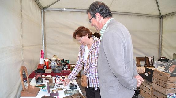 Dos personas observan objetos en un expositor situado en el entorno del Arco de San Basilio.