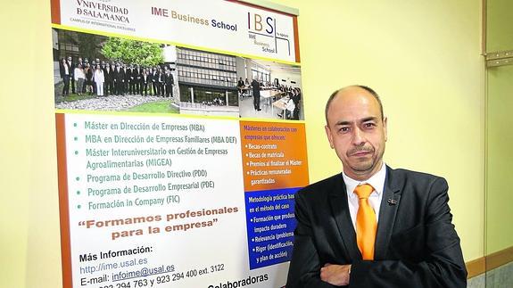 El director de IME Business School,Jesús Galende, junto a un cartel que informa sobre la oferta de la escuela de negocios. 