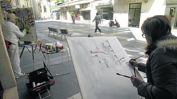 Dos participantes pintan en la calle Juan de Castilla.
