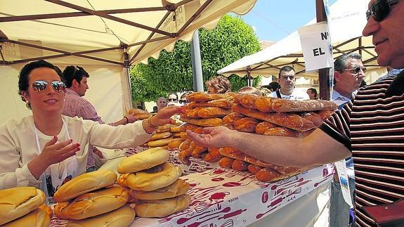 Una joven atiende a un cliente en uno de los puestos de panadería de la feria.