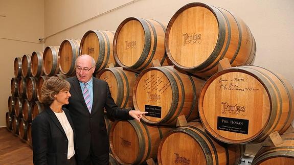 La ministra de Agricultura y el comisario europeo observan la barrica con el nombre de Isabel García Tejerina junto a la de Phil Hogan.