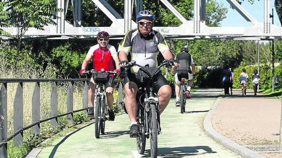 Dos usuarios de bicicleta pasean sonrientes por uno de los carriles bici de la capital. 