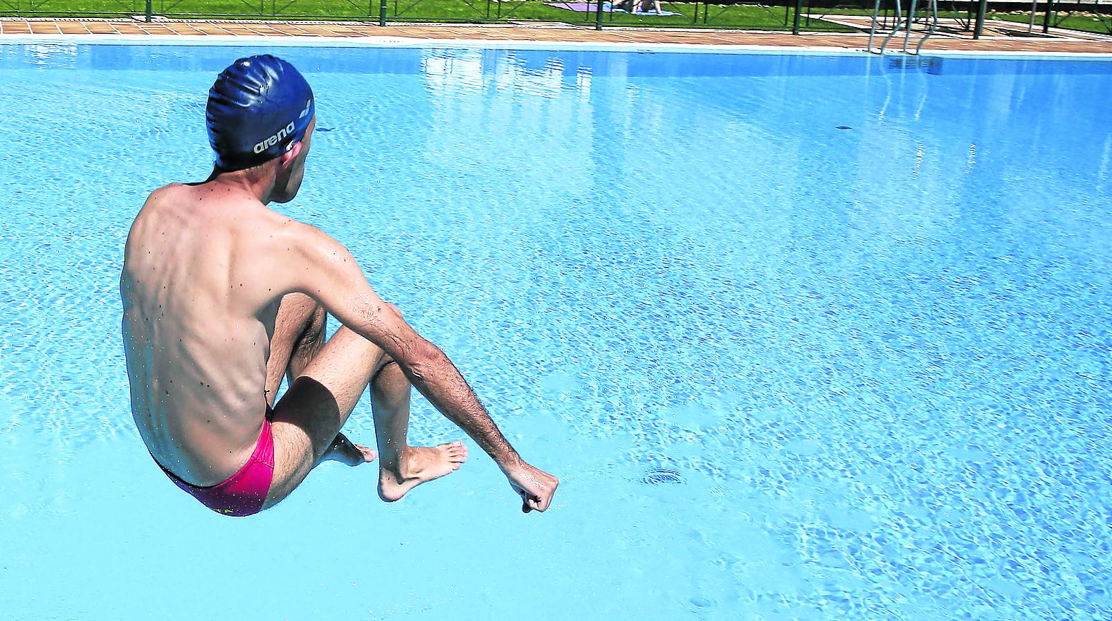 Un joven se lanza a una piscina. 