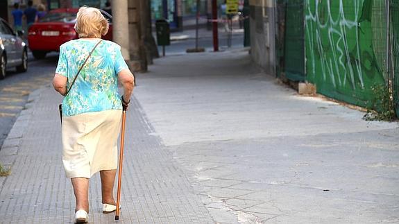 Una persona mayor pasea por una calle de Segovia.