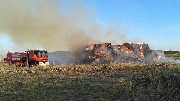 Un camión de bomberos, junto a las pacas de paja afectadas por el fuego. 