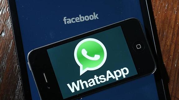 Un IPhone con el logo de Whatsapp sobre el logo de Facebook