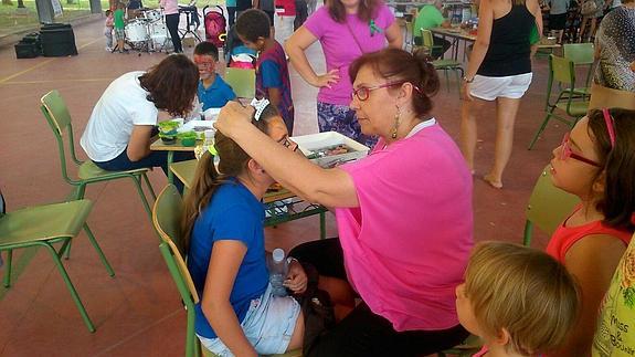 Una vecina pinta la cara a una niña. 