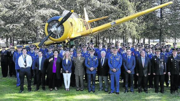 Foto de familia de alumnos y profesores y de los invitados junto a uno de los aviones históricos de la base aérea. 