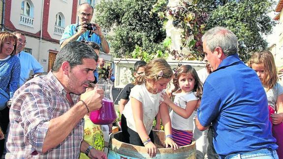 Niños y mayores degustan el mosto en la fiesta de la vendimia.