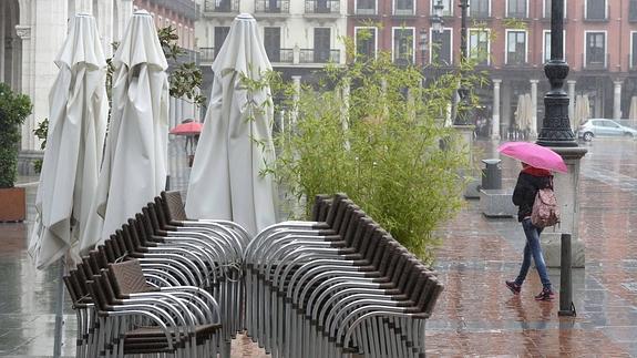 Una mujer pasea bajo su paraguas por la Plaza Mayor de Valladolid.