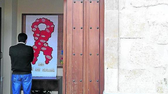Alfredo observa un lazo rojo de la lucha contra el Sida en la entrada de la Casa Samuel. 