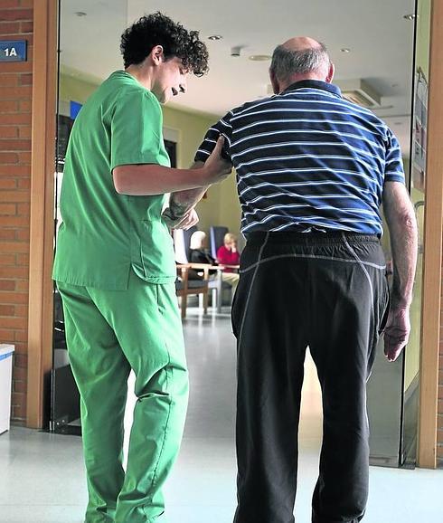 Una cuidadora ayuda a uno de los pacientes a caminar. 