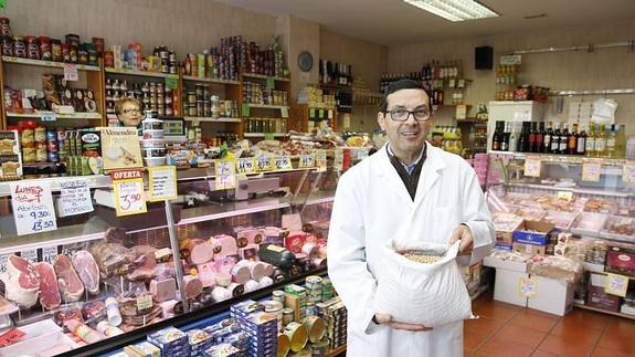 Santiago Gómez, de procedencia riosecana, posa con un saco de garbanzos entre los innumerables productos que venden en su tienda.
