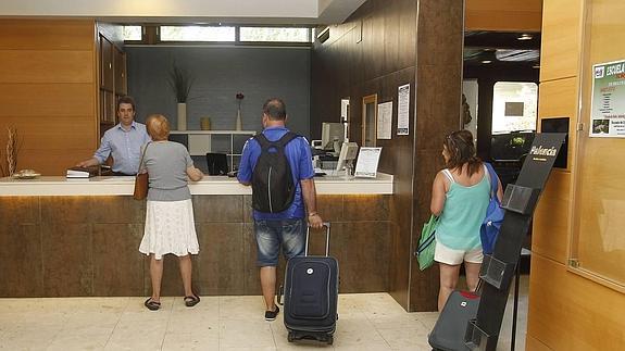 Unos clientes esperan en la recepción del hotel. 