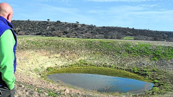Un ganadero observa la charca, prácticamente seca, de su parcela.